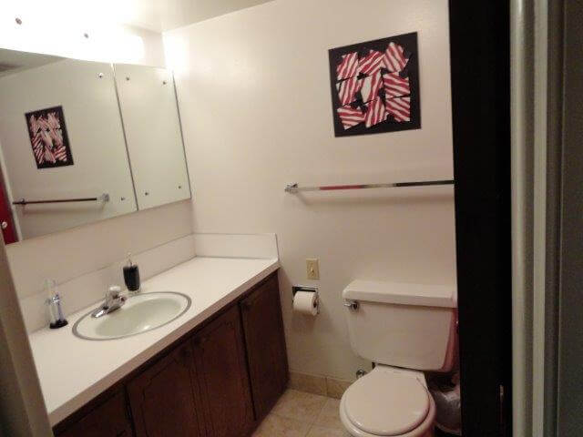 Bathroom, with dark wood vanity, white sink, mirror, and white toilet at Crestview 457 East, unfurnished family housing.