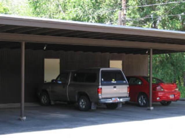 Covered parking for six vehicles, showing two cars and doors to extra storage at Crestview 457 East, family housing.