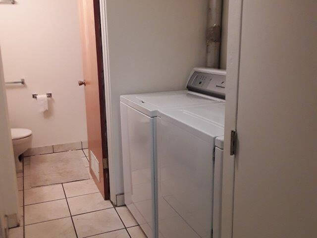 Laundry area with washer and dryer leading into bathroom with vanity, toilet, and tub/shower (behind door).