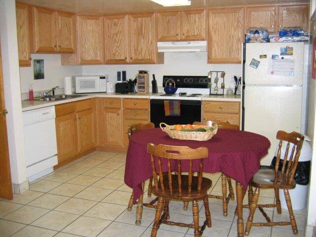 Kitchen with oak cabinets, almond countertops, dishwasher, microwave, oven, refrigerator, and wood table/chairs.