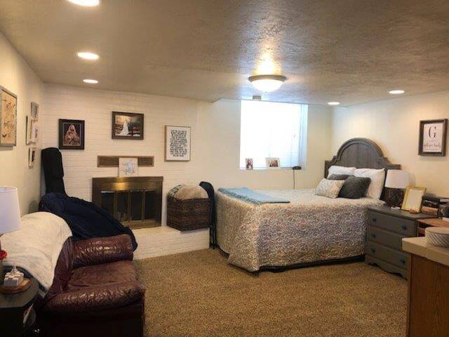 Living and bedroom area with loveseat, large window, queen bed and side tables, (twin bed provided with apt).