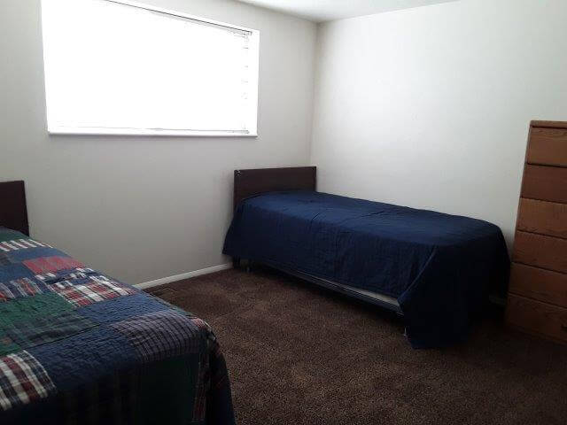 Shared-bedroom 1 with two twin beds, 6-drawer oak dresser, and large window